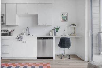 A kitchen with white cabinets and a black chair.